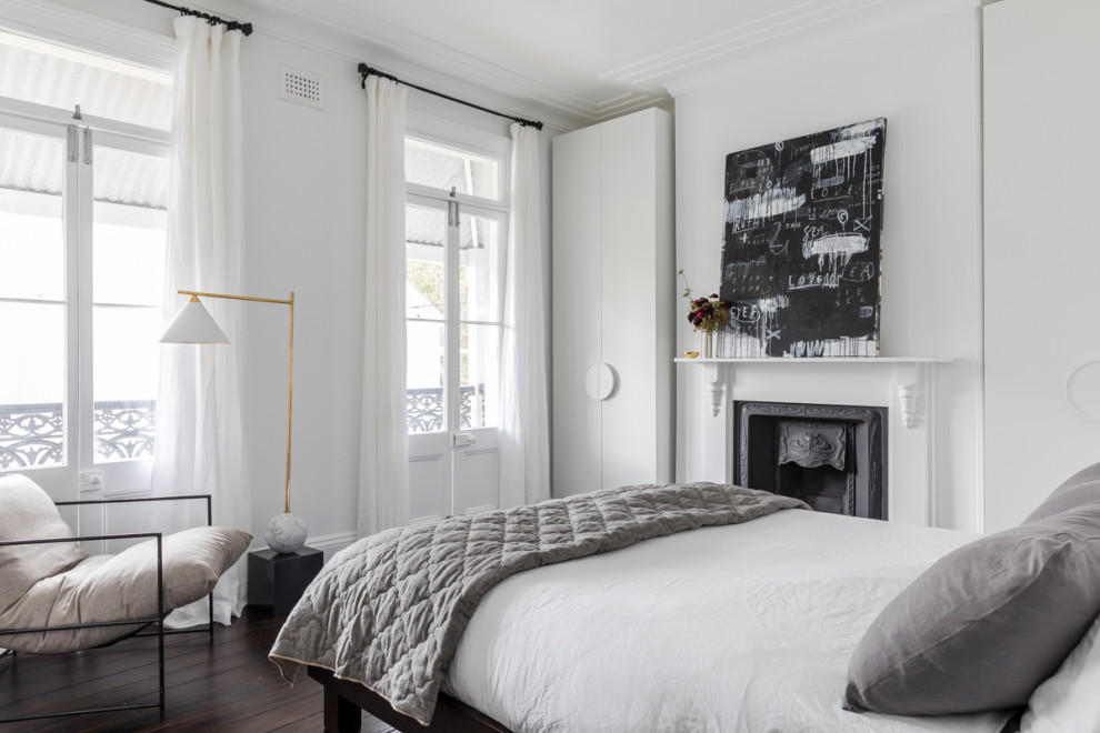 Esempio di una camera matrimoniale design con pareti bianche, parquet scuro, camino classico e pavimento marrone