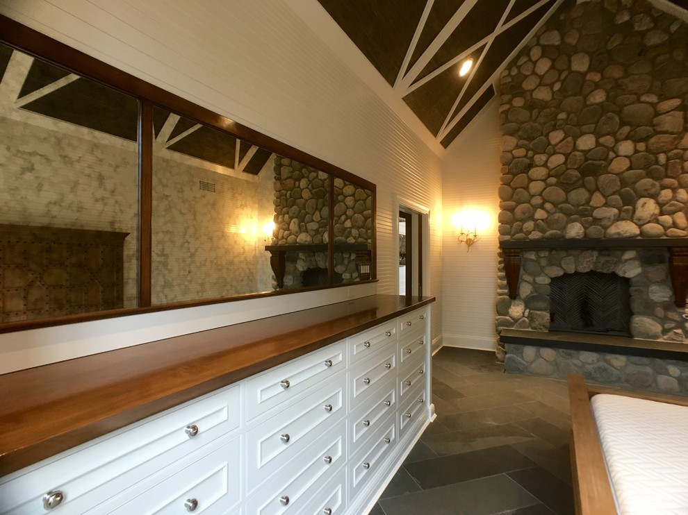 Geräumiges Klassisches Hauptschlafzimmer mit weißer Wandfarbe, Kamin, Kaminumrandung aus Stein und Schieferboden in Milwaukee