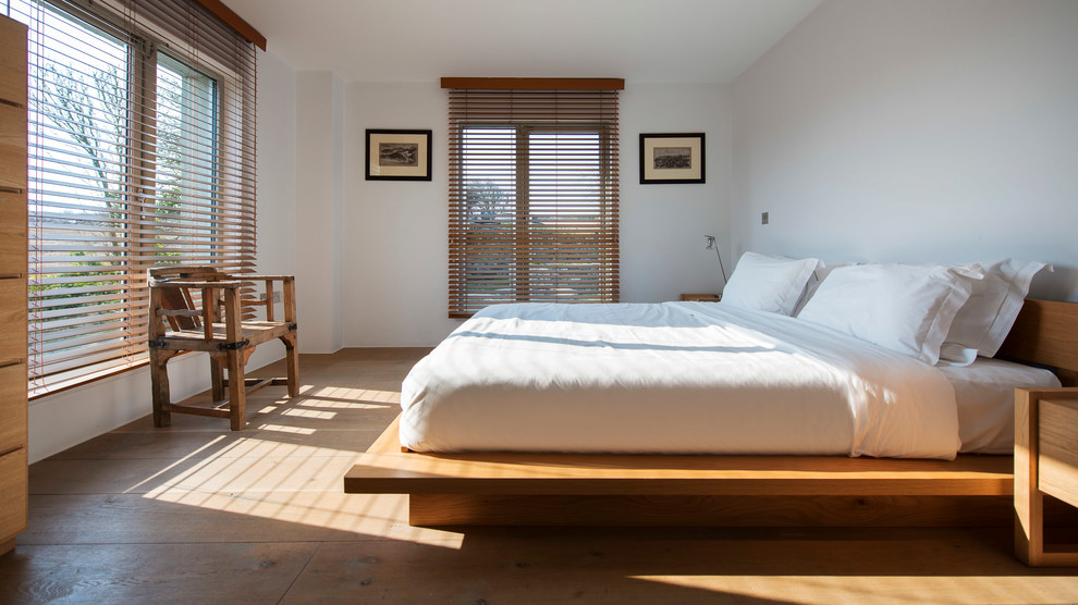 Imagen de dormitorio nórdico con paredes blancas y suelo de madera en tonos medios