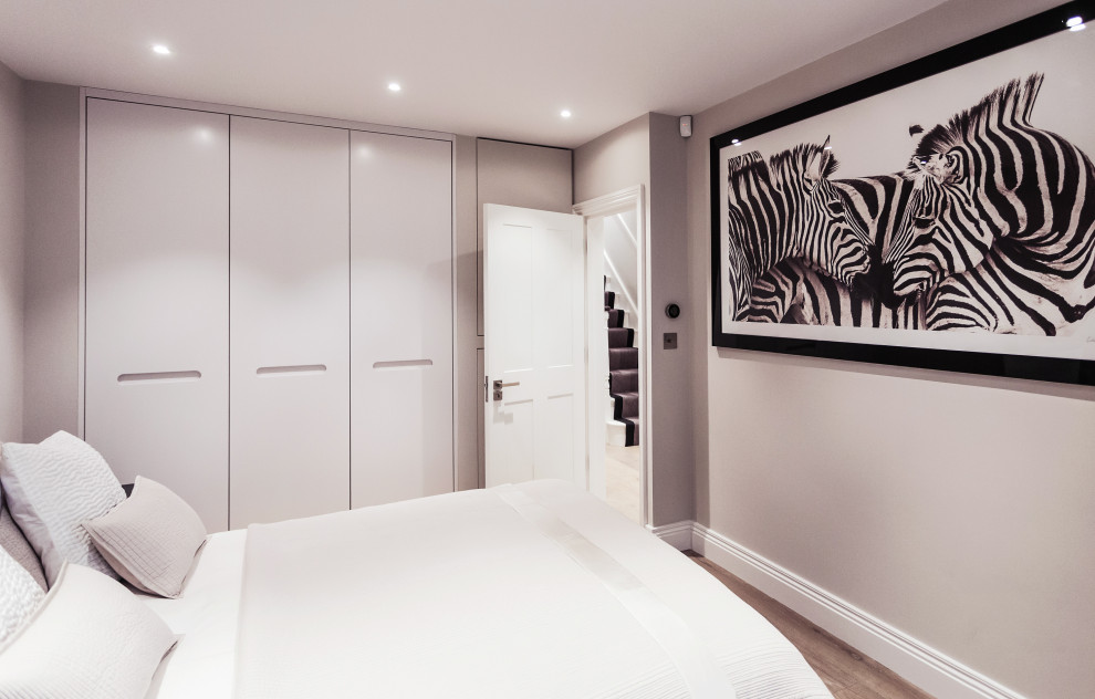 Imagen de dormitorio principal de tamaño medio con paredes blancas, suelo laminado y suelo marrón