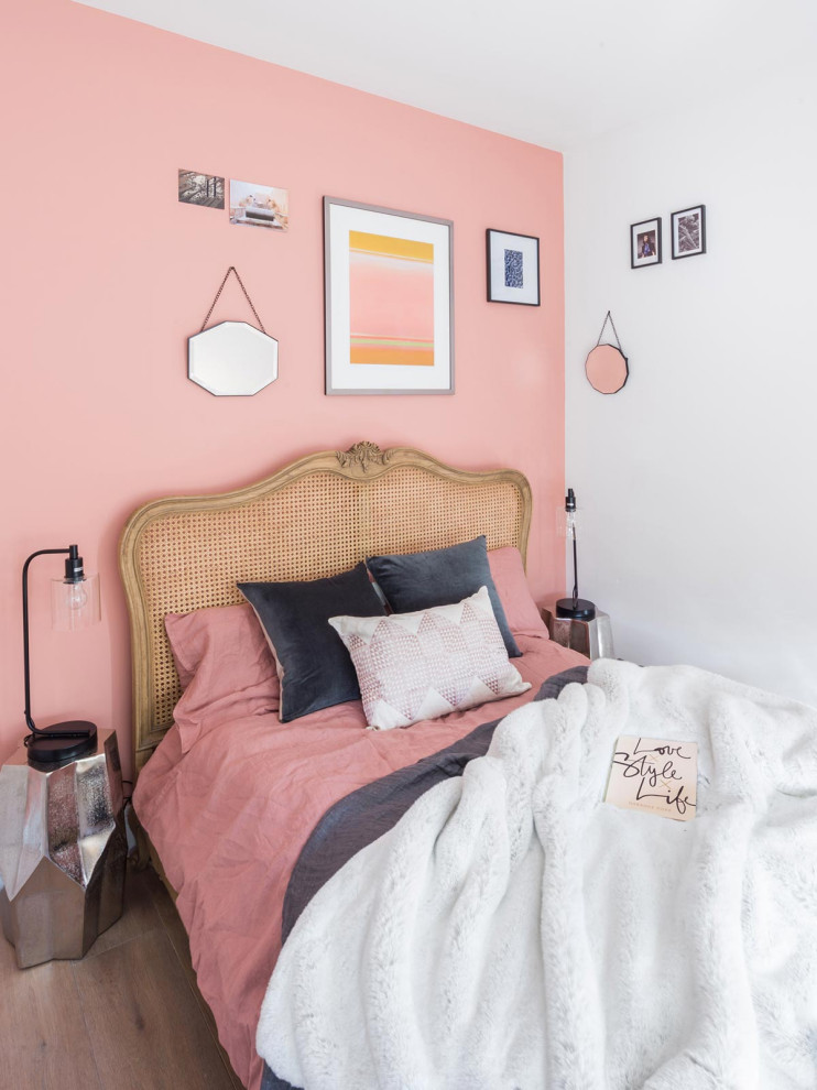 Cette image montre une petite chambre parentale avec un mur rose, sol en stratifié, aucune cheminée et un sol marron.