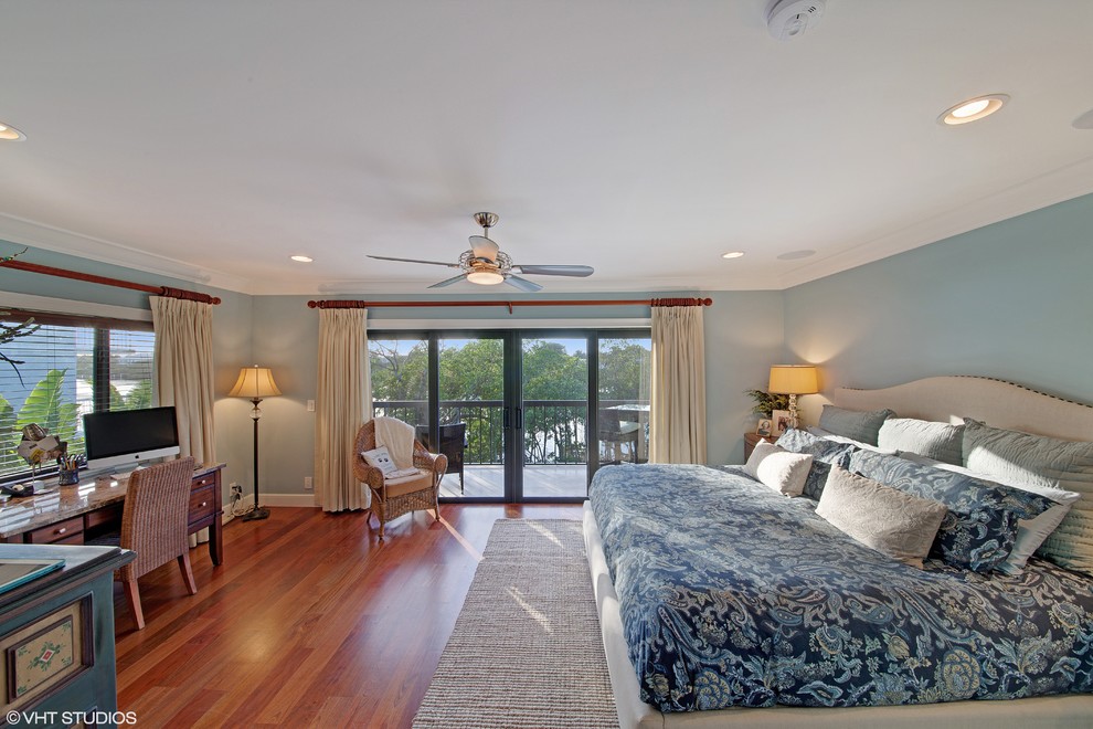 Modelo de dormitorio principal marinero de tamaño medio con paredes azules y suelo de madera en tonos medios