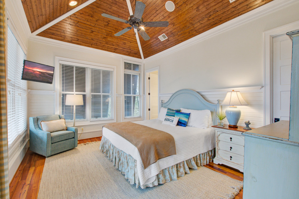 Großes Maritimes Hauptschlafzimmer mit beiger Wandfarbe, braunem Holzboden, braunem Boden, gewölbter Decke, Holzdecke und vertäfelten Wänden in Charleston
