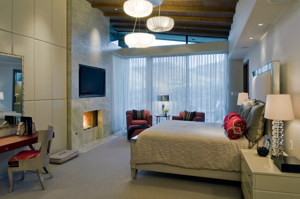 Пример оригинального дизайна: большая хозяйская спальня в стиле модернизм с бежевыми стенами, ковровым покрытием, стандартным камином и фасадом камина из камня
