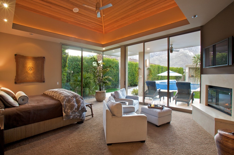 This is an example of a large contemporary master bedroom in Los Angeles with beige walls, carpet, a corner fireplace and a stone fireplace surround.