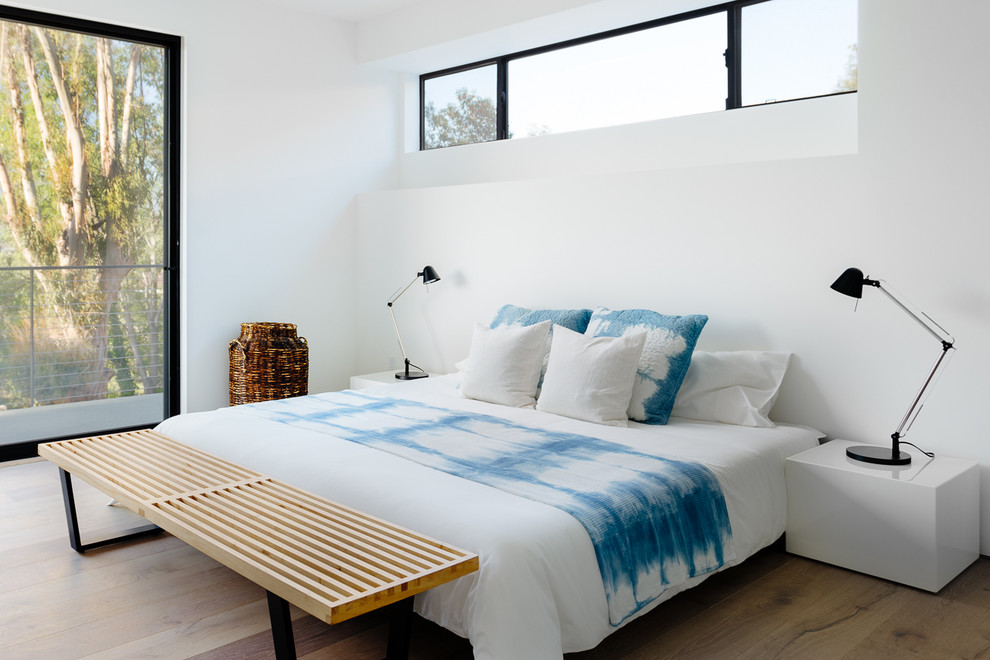Immagine di una camera da letto design con pareti bianche e parquet chiaro