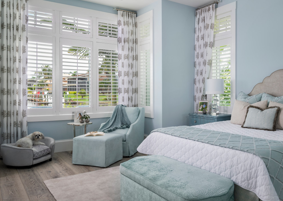 Imagen de dormitorio principal y abovedado costero con paredes azules, suelo de madera en tonos medios, suelo marrón y machihembrado