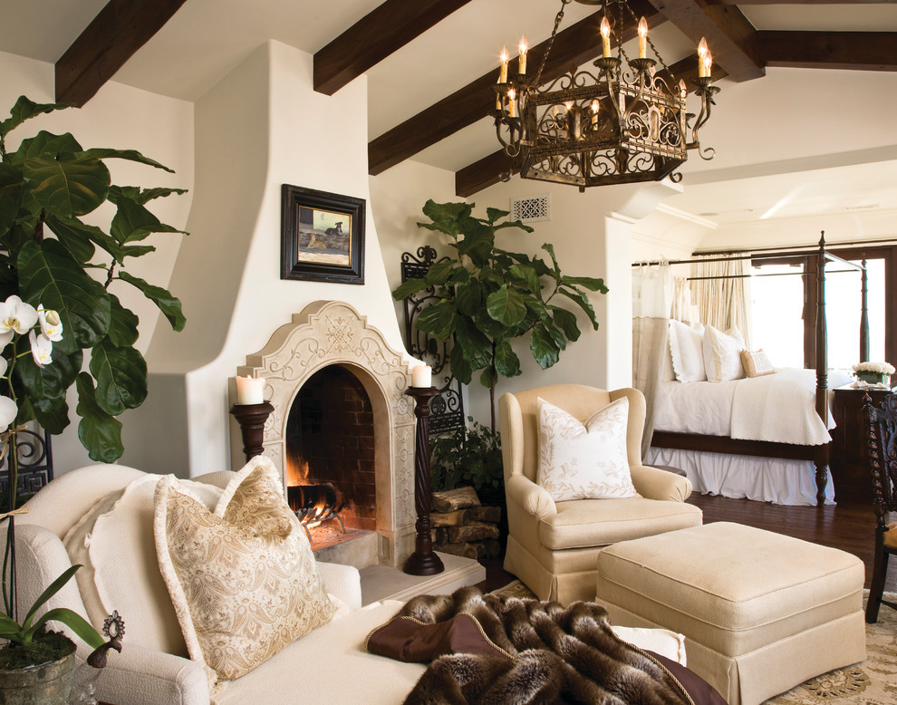 サンディエゴにある広い地中海スタイルのおしゃれな主寝室 (標準型暖炉、濃色無垢フローリング、石材の暖炉まわり、茶色い床、白い壁)