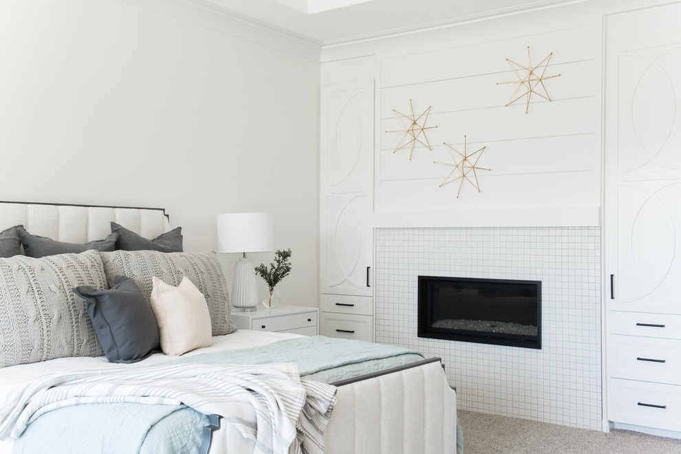 Стильный дизайн: спальня в стиле неоклассика (современная классика) с белыми стенами, ковровым покрытием, стандартным камином, фасадом камина из плитки и серым полом - последний тренд
