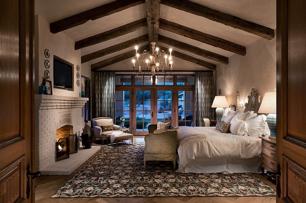 Example of a southwest master dark wood floor bedroom design in Phoenix with beige walls and a standard fireplace