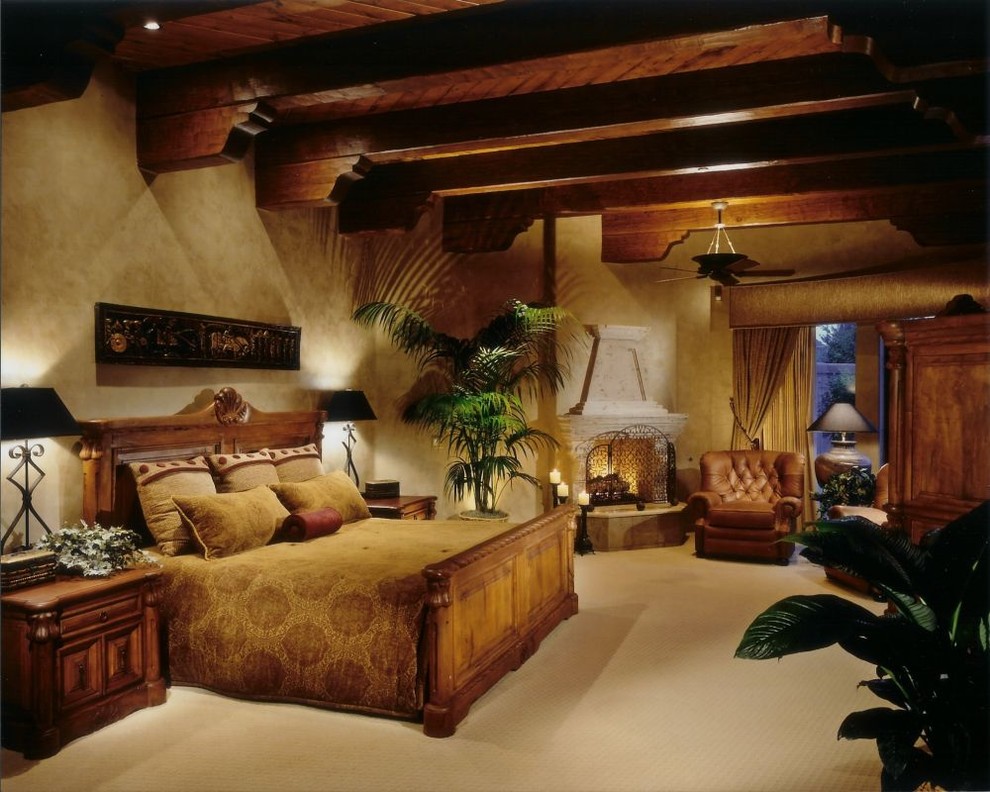Inspiration for a large mediterranean master carpeted bedroom remodel in Phoenix with beige walls, a standard fireplace and a plaster fireplace