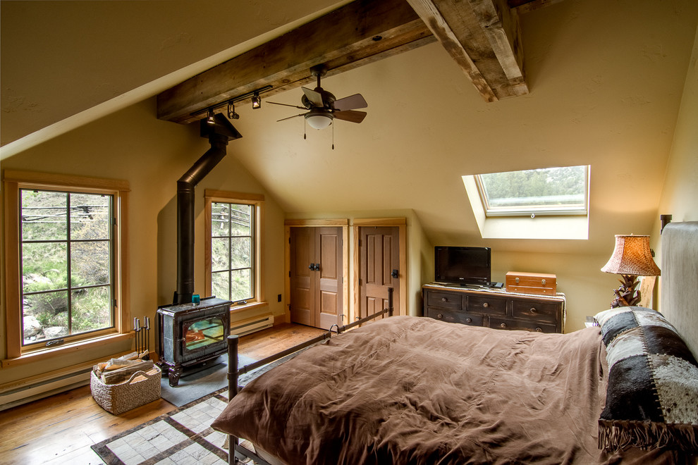 Modelo de dormitorio principal rural de tamaño medio sin chimenea con paredes beige, suelo de madera en tonos medios y suelo marrón