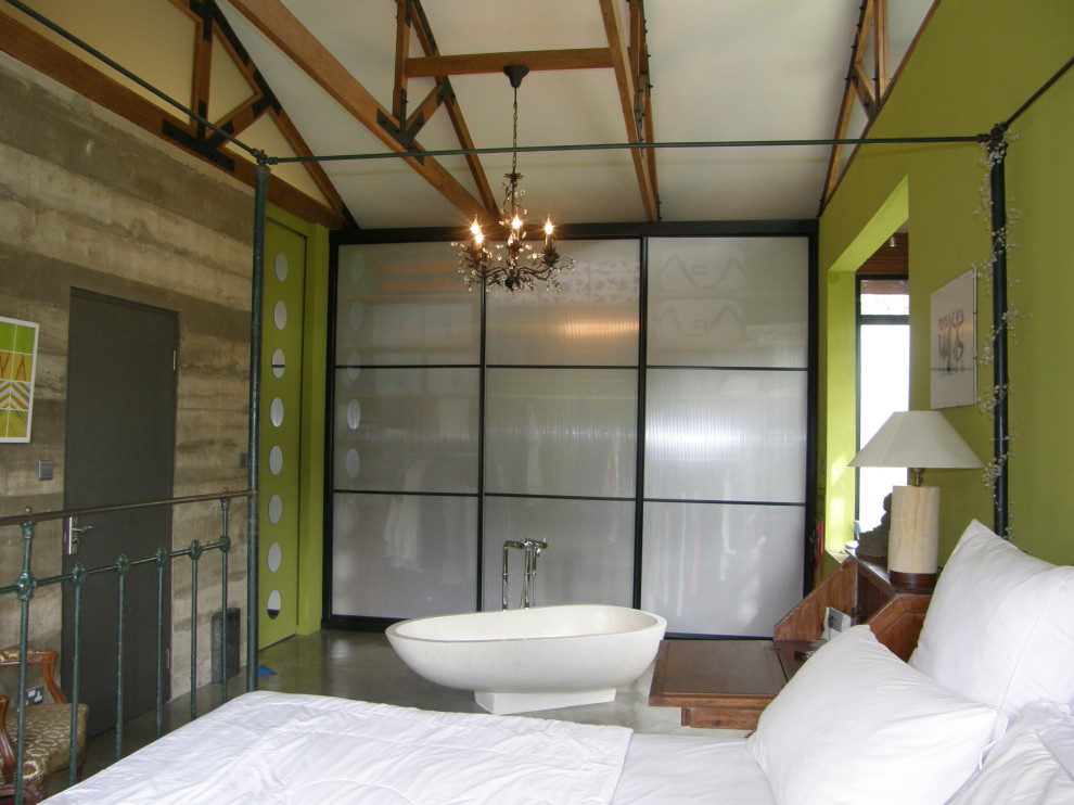 Idee per una camera matrimoniale tropicale di medie dimensioni con pareti verdi, pavimento in cemento, nessun camino e pavimento grigio