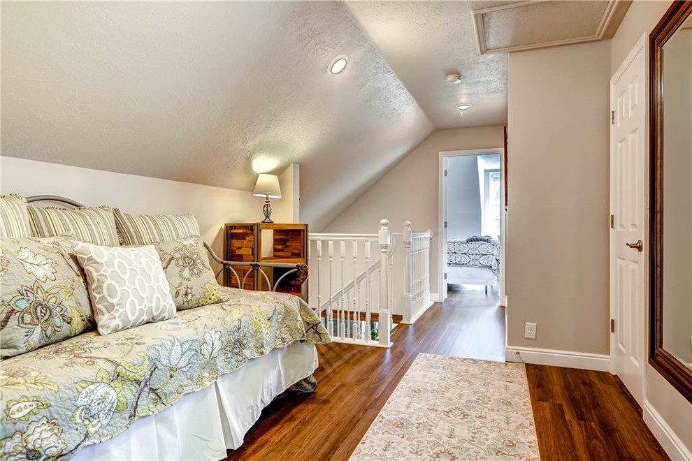 Cette photo montre une petite chambre mansardée ou avec mezzanine chic avec un mur beige, parquet foncé, aucune cheminée et un sol marron.