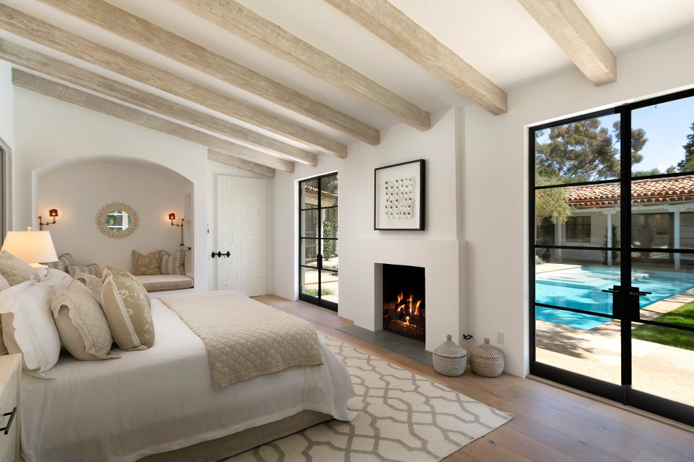 Свежая идея для дизайна: спальня в средиземноморском стиле с белыми стенами, паркетным полом среднего тона, стандартным камином и коричневым полом - отличное фото интерьера