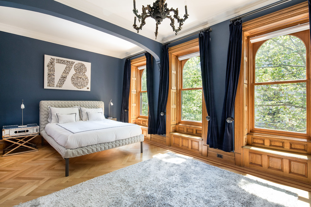 Modelo de dormitorio principal clásico grande sin chimenea con paredes azules, suelo de madera en tonos medios y suelo marrón