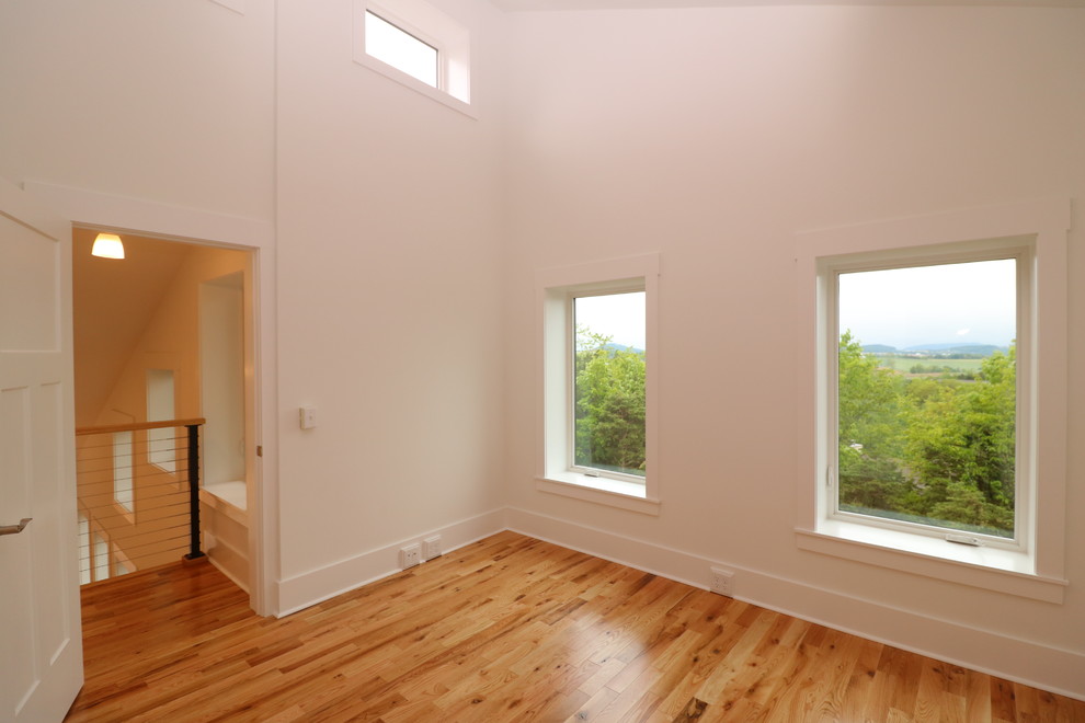Idée de décoration pour une chambre parentale minimaliste de taille moyenne avec un mur blanc, parquet clair, un sol marron et aucune cheminée.