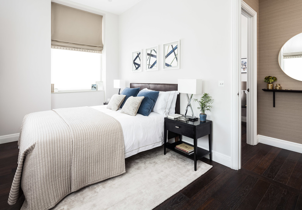 Cette image montre une petite chambre parentale design avec un mur gris, parquet foncé et un sol marron.