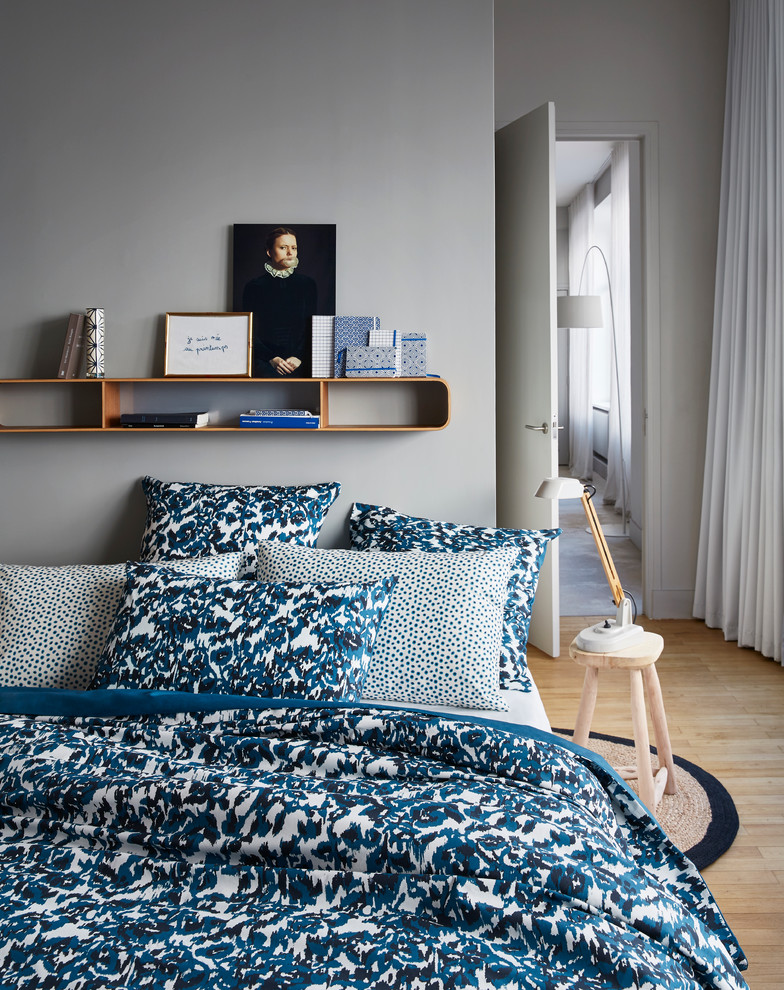 Cette photo montre une petite chambre parentale scandinave avec parquet clair et un mur gris.