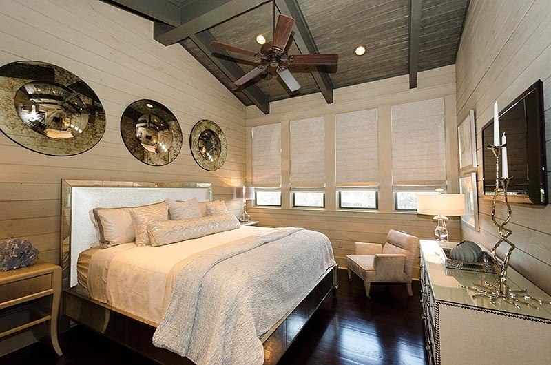 Expansive contemporary master bedroom in Miami with beige walls, dark hardwood flooring and a stone fireplace surround.