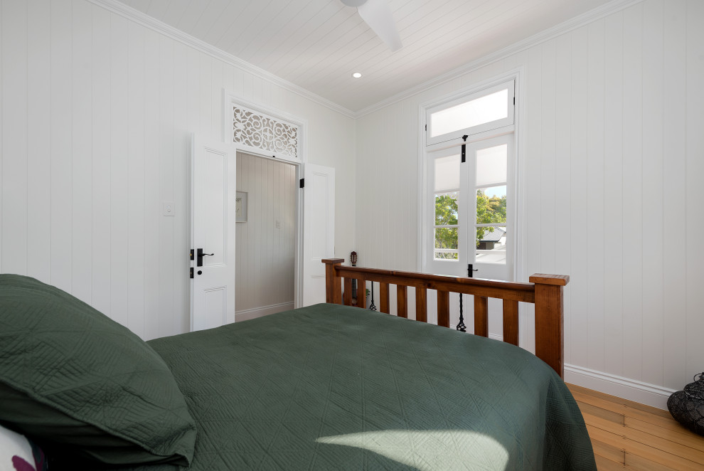 Mittelgroßes Klassisches Gästezimmer mit weißer Wandfarbe, hellem Holzboden, gelbem Boden, Holzdecke und Wandpaneelen in Brisbane