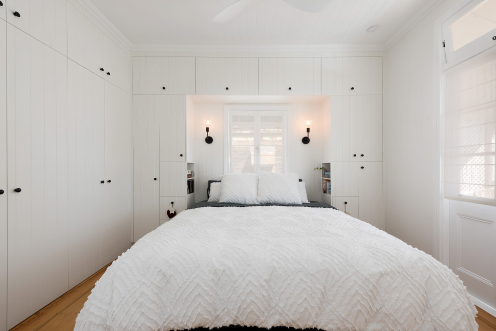 Ejemplo de dormitorio principal tradicional de tamaño medio con paredes blancas, suelo de madera clara, suelo amarillo, madera y panelado