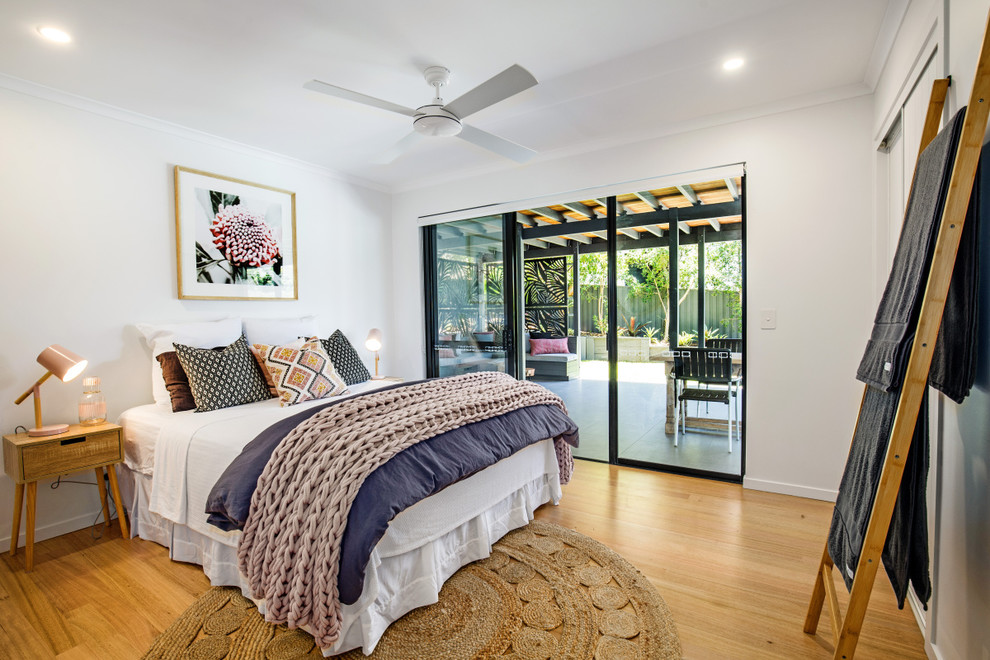 Modelo de dormitorio actual con paredes blancas, suelo de madera en tonos medios y suelo marrón