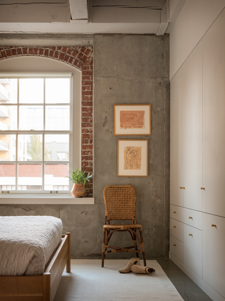 Immagine di una camera da letto industriale con pareti grigie, pavimento in cemento e pavimento grigio