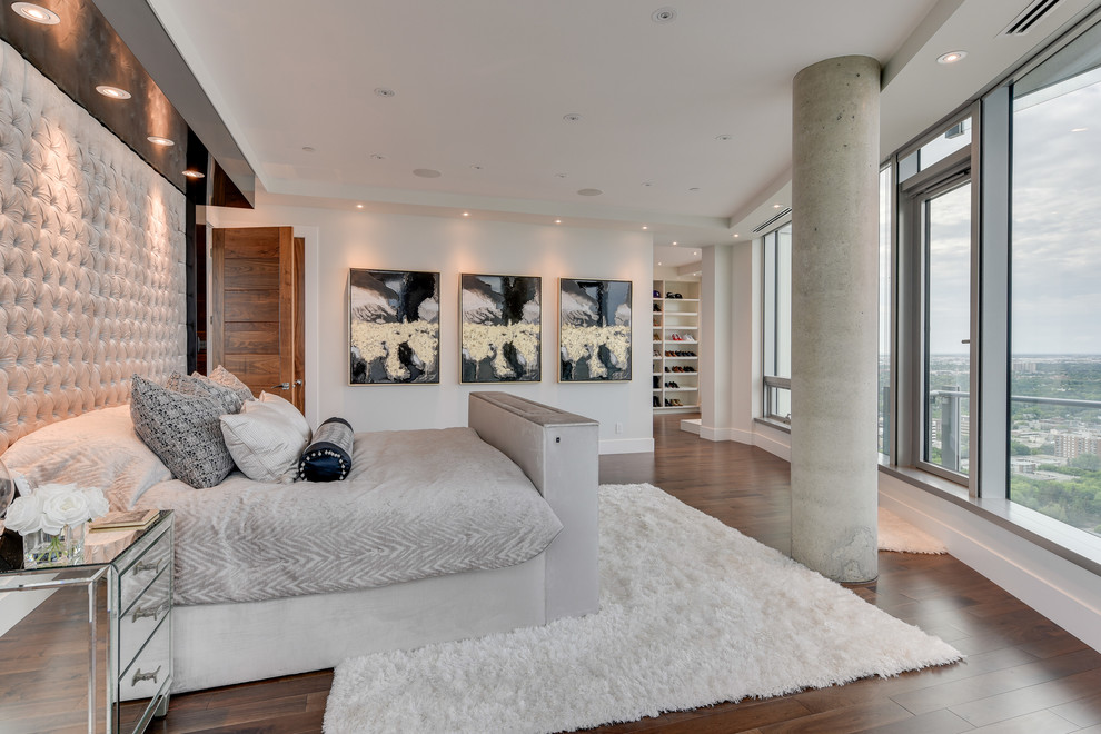 This is an example of an expansive contemporary master and grey and brown bedroom in Calgary with medium hardwood flooring, beige walls, no fireplace and brown floors.