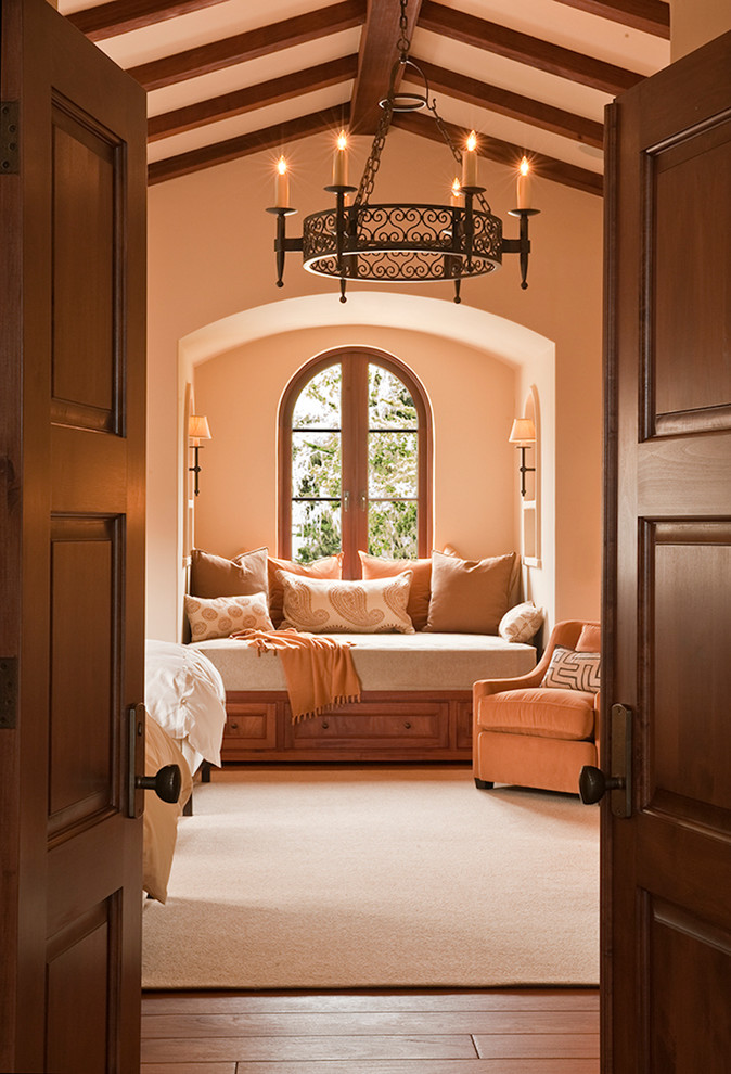 На фото: гостевая спальня (комната для гостей) в средиземноморском стиле с паркетным полом среднего тона, коричневым полом и оранжевыми стенами с