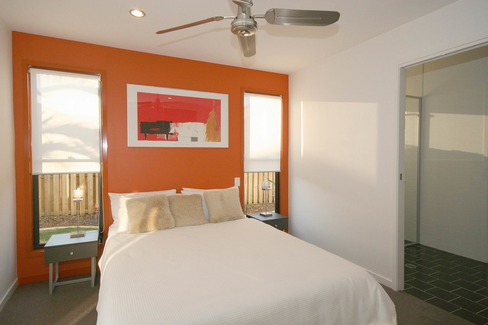 Imagen de habitación de invitados actual pequeña con parades naranjas y moqueta