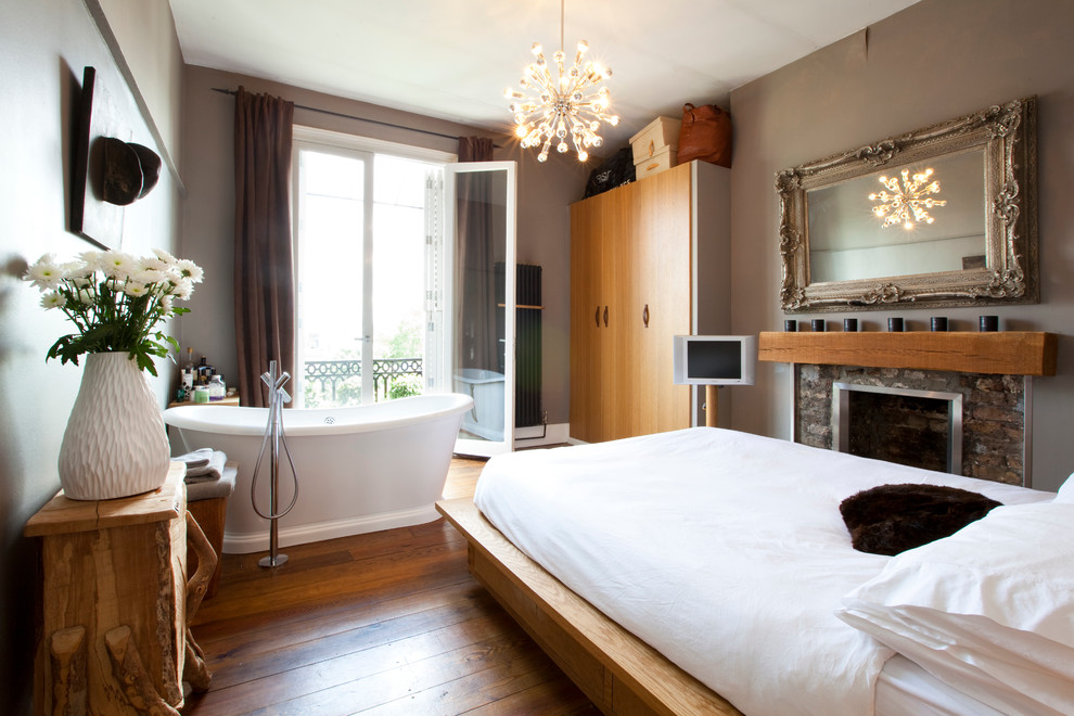 На фото: хозяйская спальня среднего размера в стиле модернизм с серыми стенами, паркетным полом среднего тона, стандартным камином и фасадом камина из кирпича