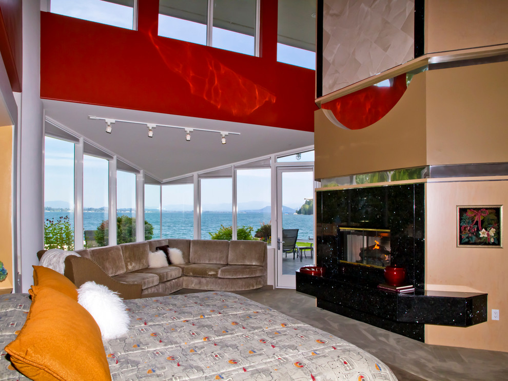 На фото: большая хозяйская спальня в стиле фьюжн с красными стенами, ковровым покрытием, стандартным камином и фасадом камина из камня с