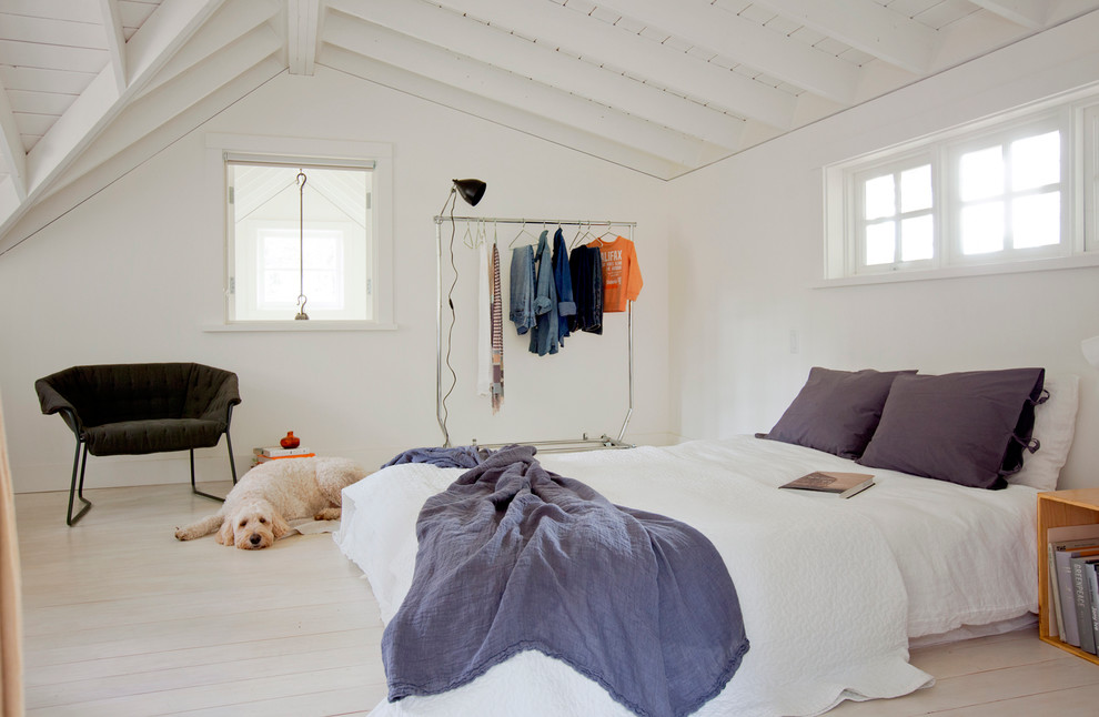 Ejemplo de dormitorio escandinavo con paredes blancas, suelo de madera clara y techo inclinado