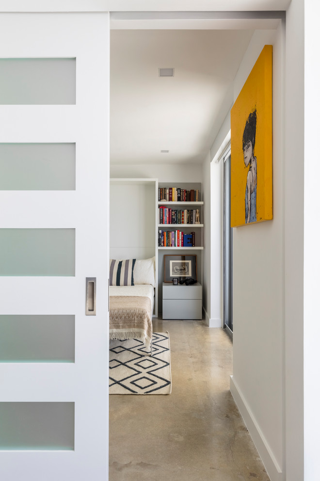 Immagine di una camera degli ospiti moderna di medie dimensioni con pareti bianche, pavimento in cemento e pavimento beige