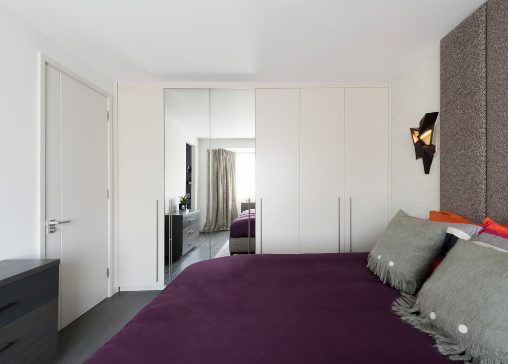 Ispirazione per una camera da letto design con pareti bianche, parquet scuro e pavimento nero