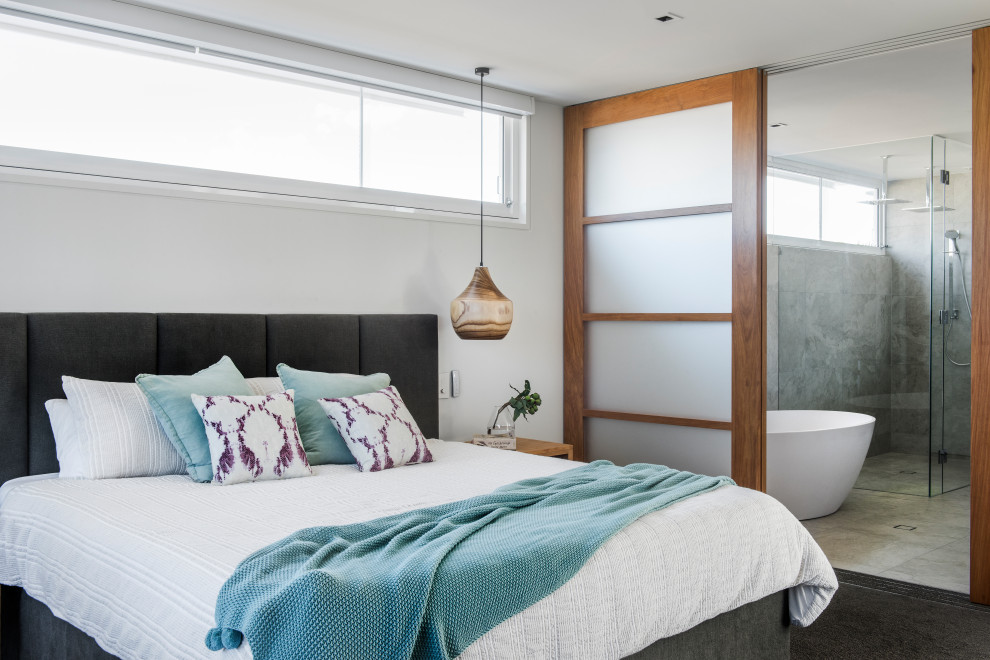 サンシャインコーストにあるビーチスタイルのおしゃれな寝室 (白い壁、カーペット敷き、黒い床)