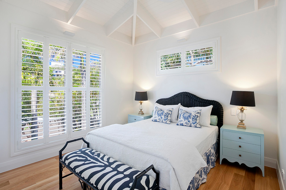 Foto de habitación de invitados costera de tamaño medio con paredes blancas y suelo de madera clara