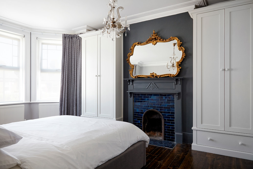 ロンドンにある中くらいなモダンスタイルのおしゃれな主寝室 (グレーの壁、濃色無垢フローリング、標準型暖炉、タイルの暖炉まわり) のレイアウト