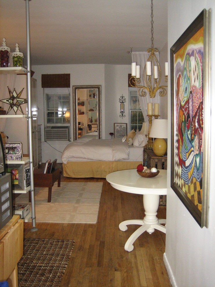 Eklektisk inredning av ett litet sovrum, med vita väggar och mellanmörkt trägolv