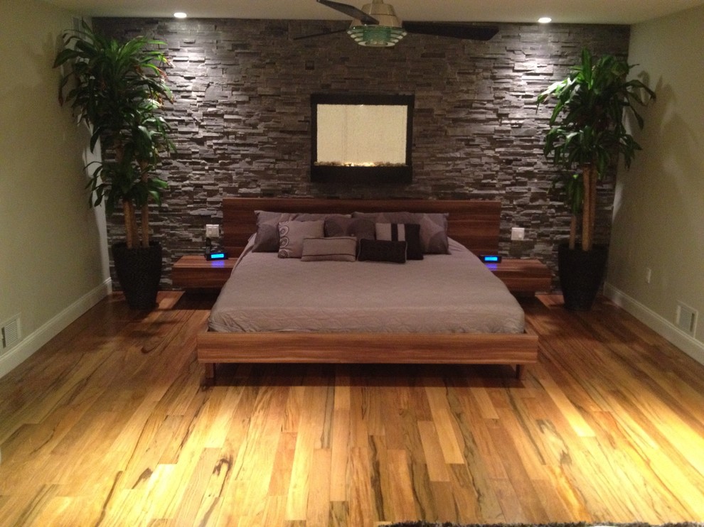 Cette image montre une très grande chambre parentale minimaliste avec un mur gris et un sol en bois brun.
