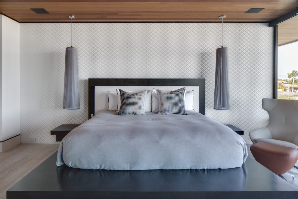 Modelo de dormitorio contemporáneo sin chimenea con paredes blancas y suelo de madera clara