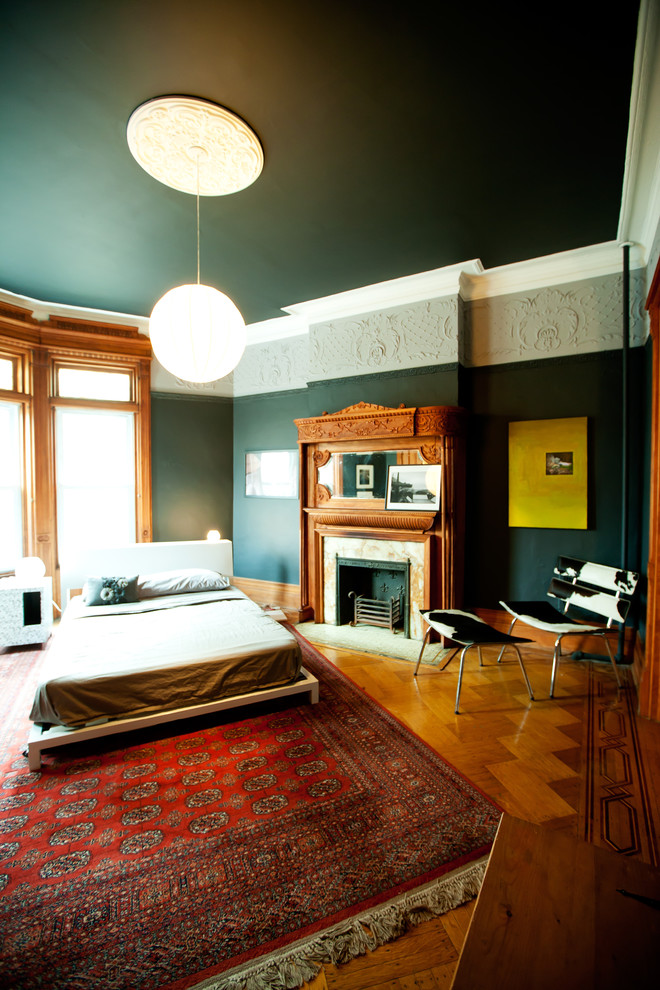 Foto di una camera da letto contemporanea con pavimento in legno massello medio e camino classico