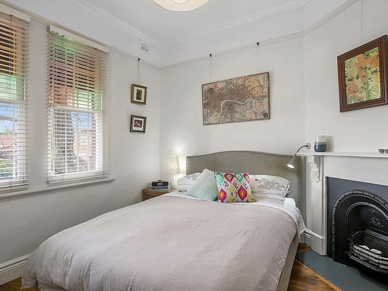 Kleines Modernes Hauptschlafzimmer mit weißer Wandfarbe, hellem Holzboden, Eckkamin und Kaminumrandung aus Holz in Sydney