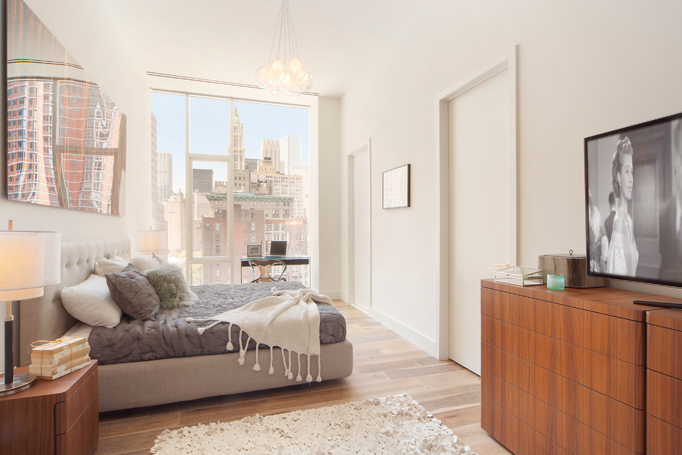 Modelo de habitación de invitados contemporánea de tamaño medio con paredes blancas, suelo de madera en tonos medios y con escritorio