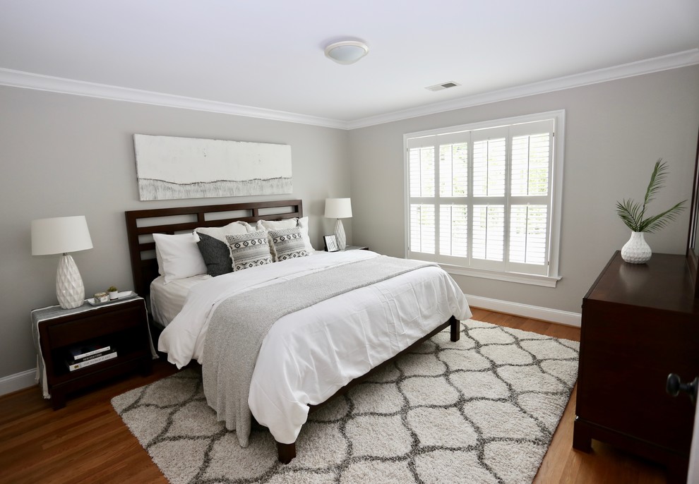 Cette photo montre une chambre d'amis éclectique de taille moyenne avec un mur gris et un sol en bois brun.