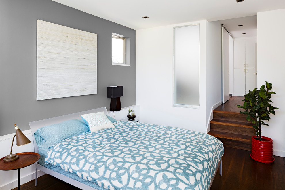 Foto de dormitorio contemporáneo con paredes grises y suelo de madera oscura