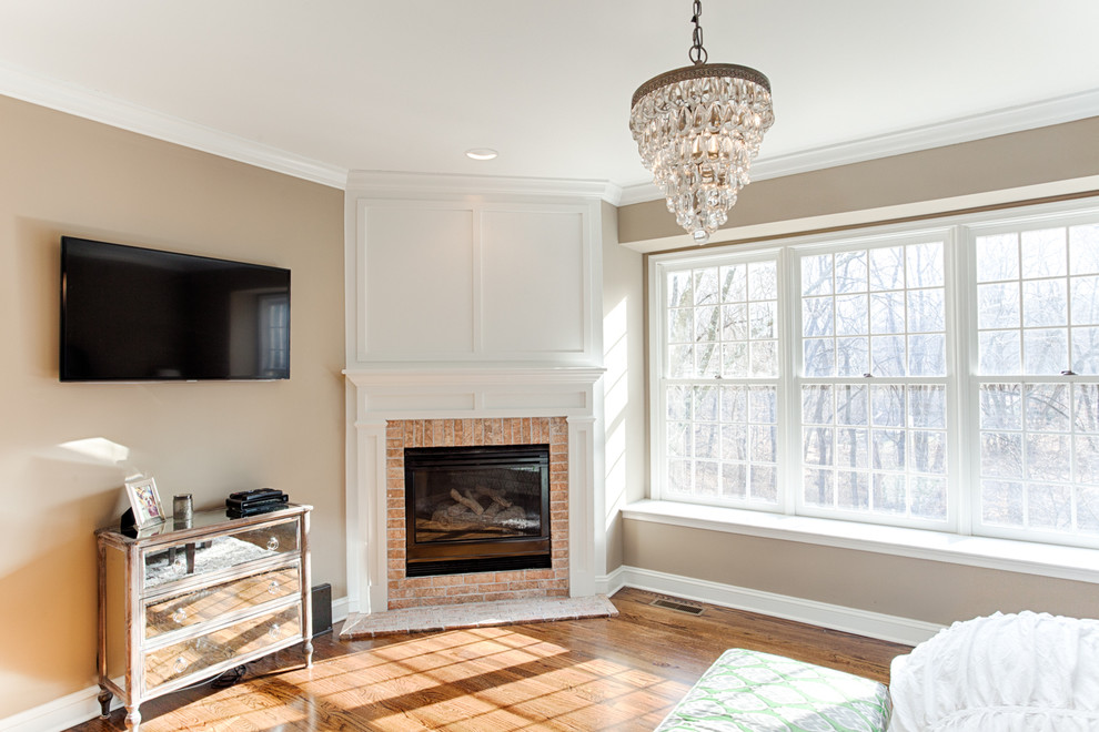 Mid-sized transitional master medium tone wood floor and brown floor bedroom photo in Philadelphia with beige walls, a corner fireplace and a brick fireplace