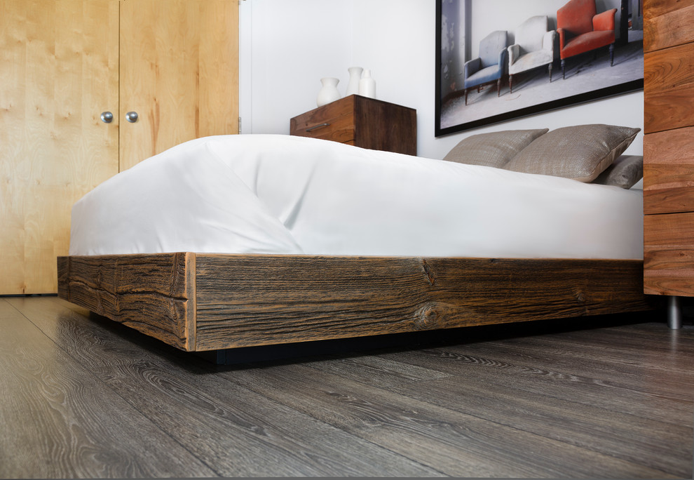 Modelo de dormitorio tipo loft industrial con paredes blancas y suelo de madera en tonos medios