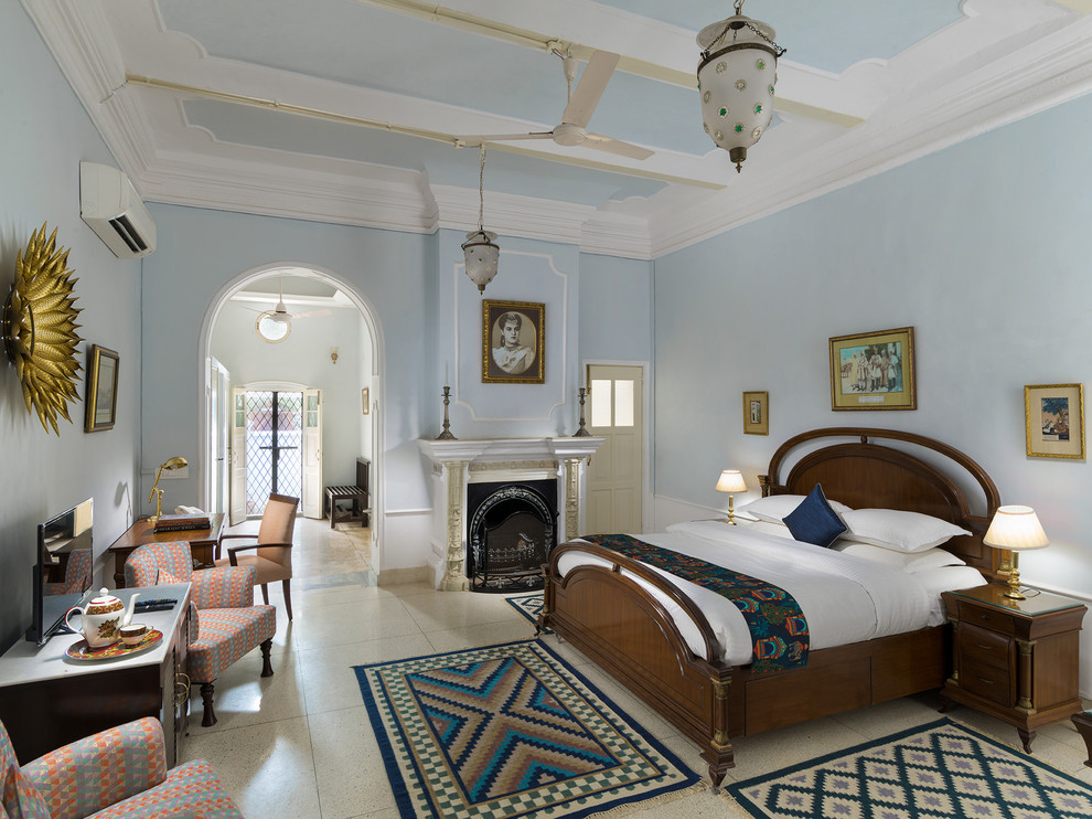 На фото: спальня среднего размера в стиле неоклассика (современная классика) с синими стенами, бетонным полом, стандартным камином, белым полом и рабочим местом